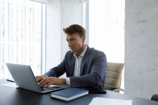 istock Serious busy middle aged businessman typing on laptop at workplace 1369578693