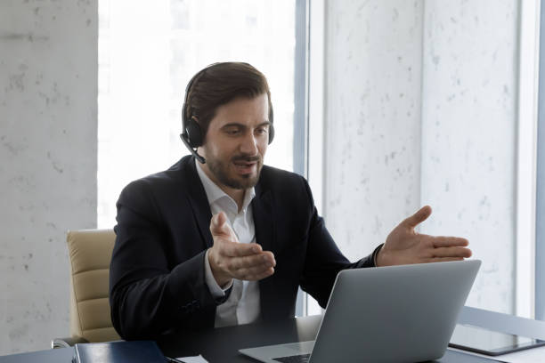 istock Serious business professional man in headphones with mic using laptop 1369578704
