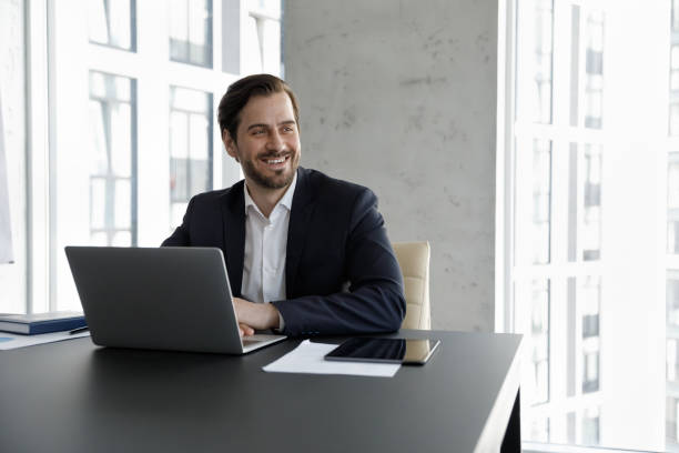 istock Happy dreamy business professional man working at laptop in office 1369578706