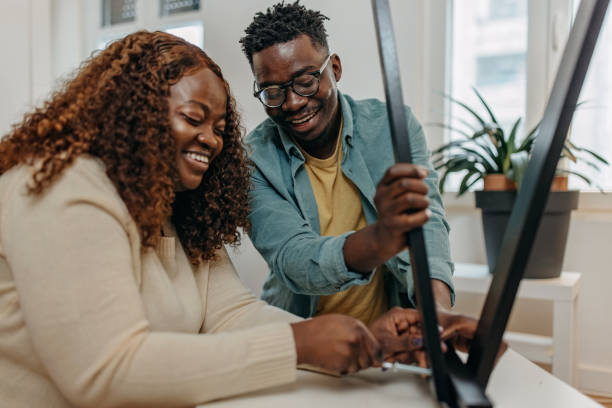 Young African-American couple assembling new furniture in the apartment Young African-American couple assembling new furniture in the apartment body positive couple stock pictures, royalty-free photos & images