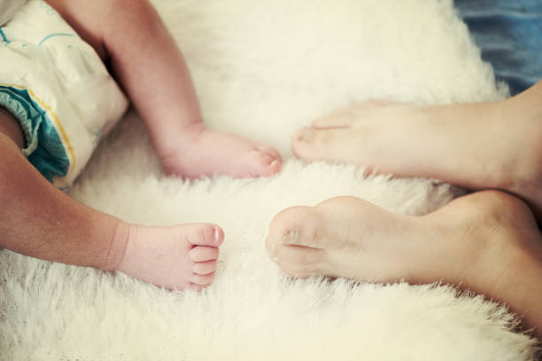 生まれたばかりの赤ちゃんの足.ハッピーファミリー、お�母さんとお父さんは赤ちゃんの足を抱きしめる。 - hands and feet flash ストックフォトと画像