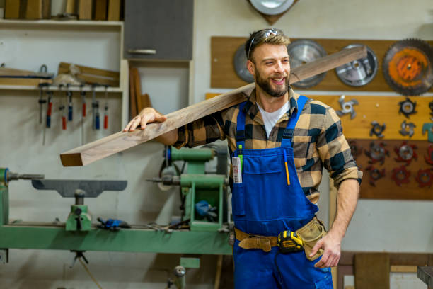istock Smiley handsome carpenter carries the long board through workshop 1369582994