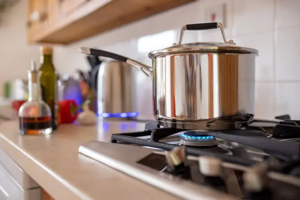 Close-up side-view shot of a cooking pot on a gas stove. Using a single ring to save extra cost of using gas as current energy prices increase.