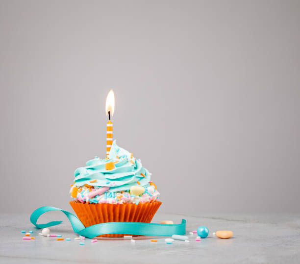 cupcake di compleanno blu con candela arancione - ribbon nobody cupcake celebration foto e immagini stock