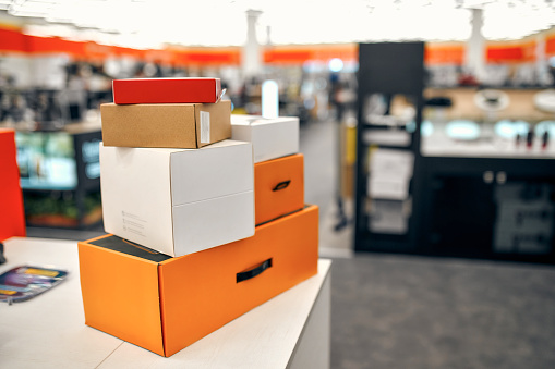 A lot of boxes with orders lying on the checkout against the background of the interior of the hall in the store of household appliances, electronics and gadgets. Home delivery.