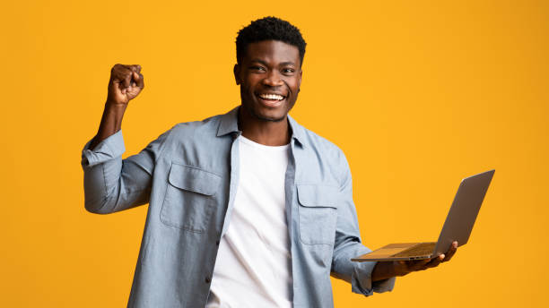 istock Happy african american guy holding laptop and gesturing 1369592858