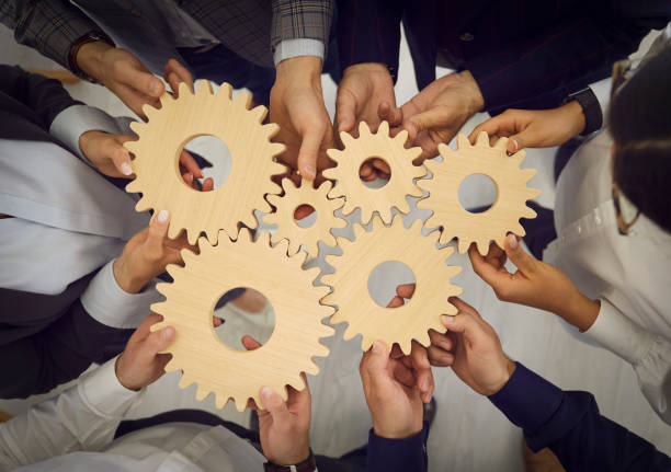 istock Group of business people join cogwheels as metaphor for teamwork and work efficiency 1369594552