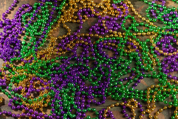 istock Mardi gras carnivale green, purple, yellow beads on rustic tile background 1369594647