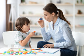 Female speech therapist curing child's problems and impediments. Little boy learning letter O with private tutor