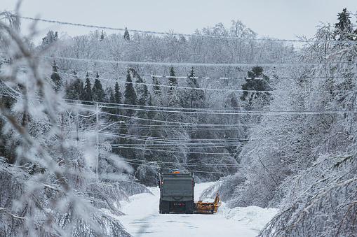 A snowplow operator works to clear snow & ice during an intense ice storm.