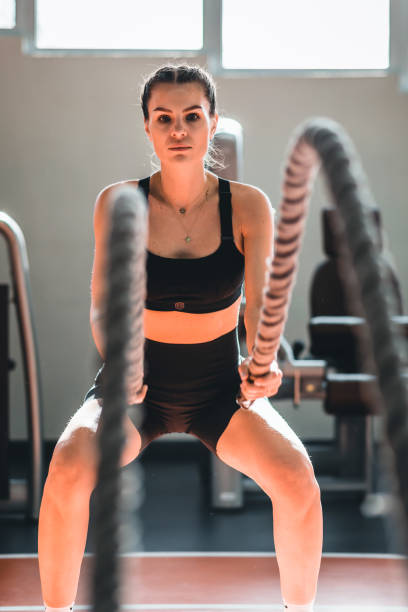 istock Athletic woman doing battle rope exercises at gym 1369598731