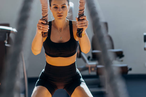 istock Fitness woman using training ropes for exercise at gym. 1369598763