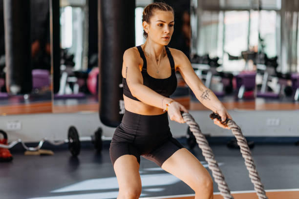 istock Fitness woman using training ropes for exercise at gym. 1369598886