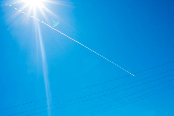Airplane flying in the blue sky among clouds and sunlight