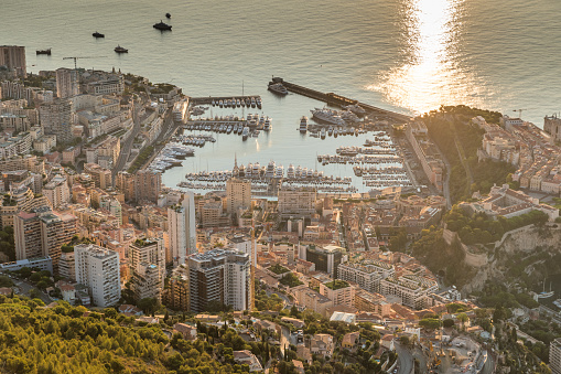 Aerial view of the Principality of Monaco at sunrise, Monte-Carlo, old town, view point in La Turbie at morning, port Hercule, Prince Palace, Mountains, Megayachts, a lot of boats, sun reflection. High quality photo