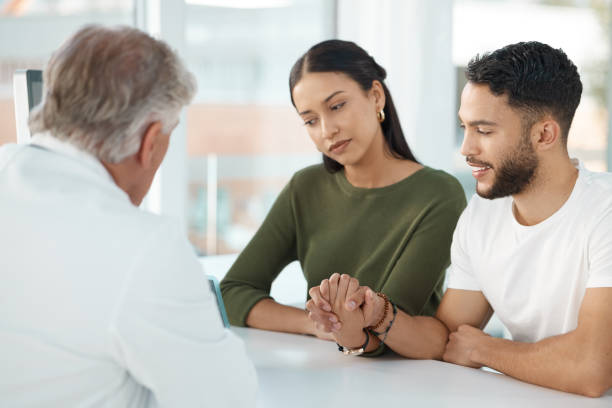 Shot of a young couple sitting with their obstetrician and holding hands during a consultation in the clinic Your results came back human fertility stock pictures, royalty-free photos & images