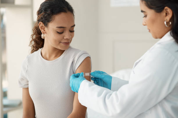 Shot of a young doctor applying a band-aid after injecting her patient during a consultation in the clinic You're all set vaccination stock pictures, royalty-free photos & images