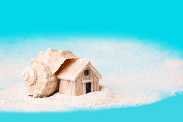 istock Toy house with a seashell on sand 1369604045
