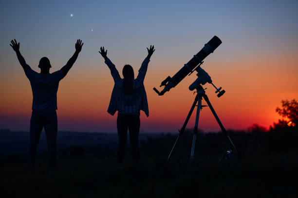 istock Couple stargazing together with a astronomical telescope. 1369606020