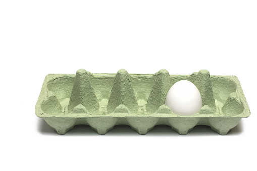 Close up of an open green cardboard egg carton box with single white egg inside on white background
