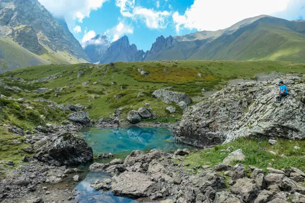 A man enjoying the Colorful Abudelauri mountain lakes in the Greater Caucasus Mountain Range in Georgia,Kazbegi Region. Trekking and outdoor travel.Alpine pastures.Lake Reflection.Green lake