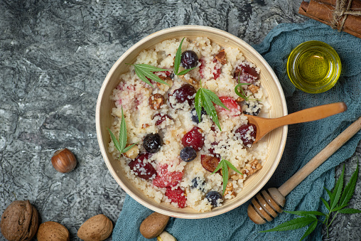 Couscous with nuts and fresh fruit in a bowl on a wooden gray background. Sweet dessert with honey. Stock photo.