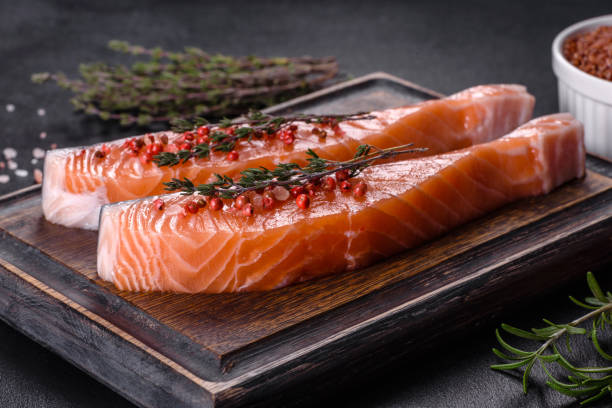 istock Fresh salmon fillets on black cutting board with herbs and spices 1369616017
