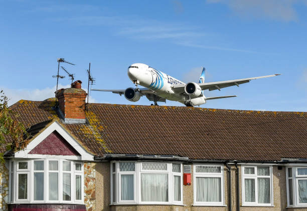 Passenger jet flying low of houses on the approach to an airport London, England - November 2018: Egyptair Boeing 777 jet flying low over rooftops before landing. britain british audio stock pictures, royalty-free photos & images