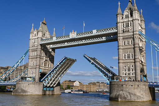 London, England - August 2022: Tower Bridge with road deck raised to allow a ship to pass on the River Thames.