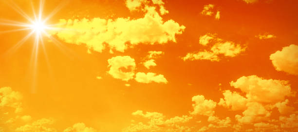 Bright glowing sun on orange sky background with clouds