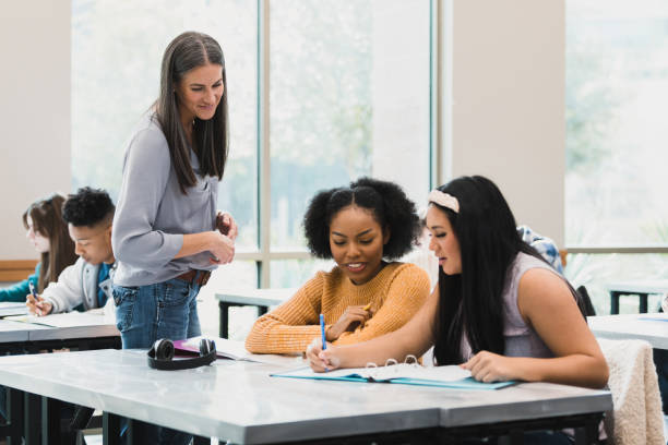 istock Female teacher walks around room supervising student work 1369617368