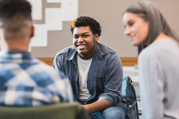 Unrecognizable teacher smiles as teen welcomes new student stock photo