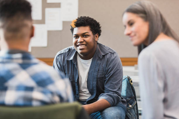 Unrecognizable teacher smiles as teen welcomes new student The unrecognizable female teacher is happy when the teenage boy smiles and welcomes an unrecognizable male student. teens interacting photos stock pictures, royalty-free photos & images