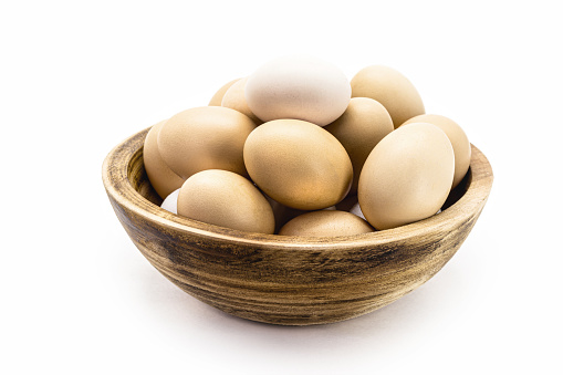 Brazilian free-range chicken eggs in rustic wooden bowl with white background and copyspace