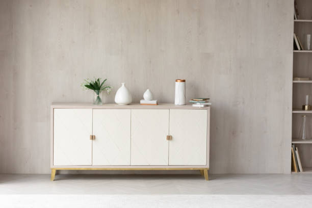 White modern dresser minimalistic furniture in empty room White modern dresser minimalistic furniture in empty room on grey wall background, small cupboard with decor, vases and lily of the valley flowers bouquet, cozy apartment house interior concept chest furniture stock pictures, royalty-free photos & images