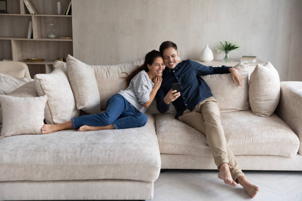 istock Happy woman and man hugging, using smartphone together 1369617661