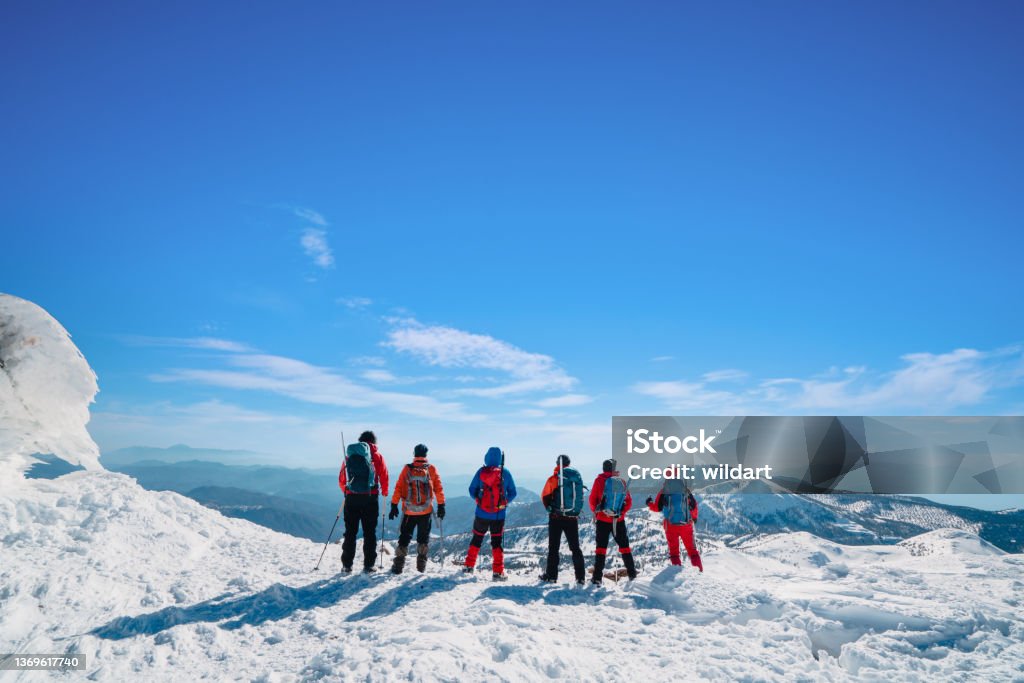 Mountain alpine climbing team is watching the scenery in high altitude mountain peak in winter Climbers are enjoying the success of climbing the summit of the high altitude mountain  in winter time in Turkey ,recorded during a climbing expedition. Mountain Peak Stock Photo