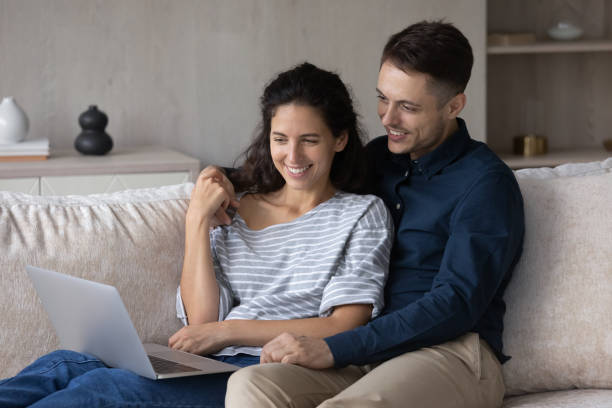 istock Happy couple using laptop together, relaxing on couch 1369617787