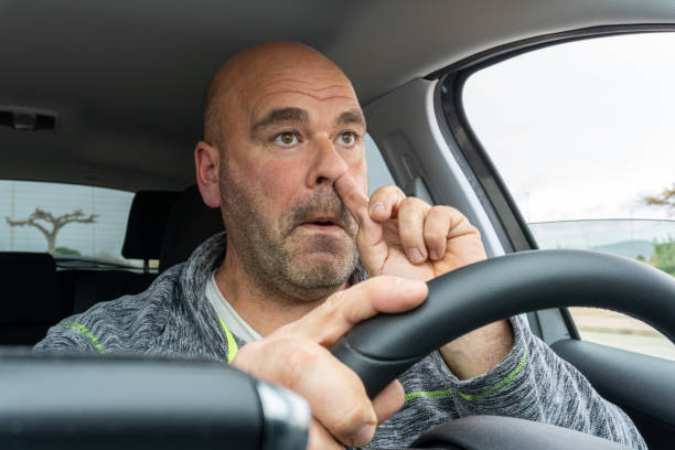 Middle aged man picking his nose Middle aged man picking his nose driving a car. Distracted stock pictures, royalty-free photos & images