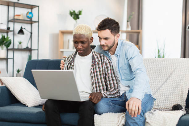 istock Multi ethnic couple of two gays using laptop for video chat 1369617923