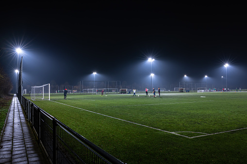 Waddinxveen, Netherlands - February 2022: Soccer training section  in the evening hours on a field illuminated by light poles.