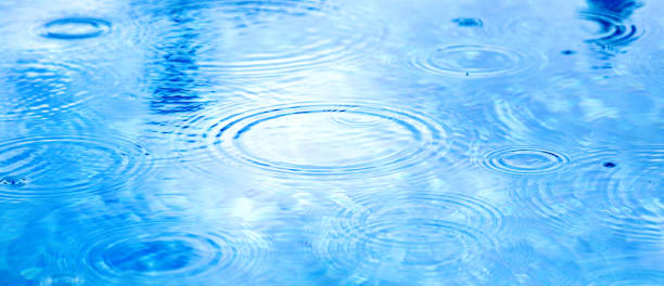 istock Stains circles on water from rain. Raindrops on pool blue water surface. blue water texture as background. Long web baner 1369619602