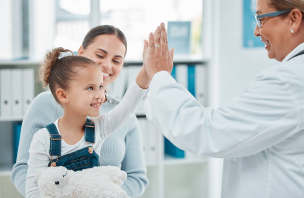 診療所で医者に高い5を与える小さな女の子のショット - pediatrician ストックフォトと画像
