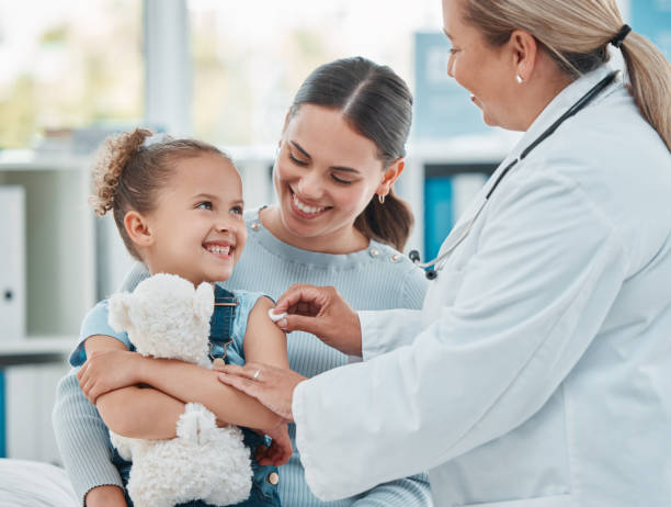 colpo di un medico che usa un batuffolo di cotone sul braccio di una bambina mentre somministra un'iniezione in una clinica - injecting foto e immagini stock