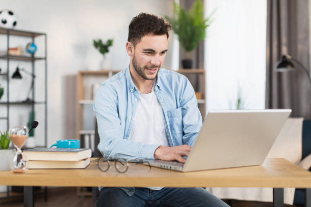 istock Man sitting at home and typing on wireless laptop 1369620752