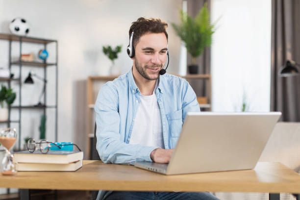 istock Man in headset having video call on laptop at home 1369620834