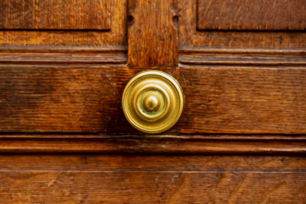 vieja manija redonda de la puerta en la vieja puerta de madera marrón. de cerca parís, francia. detalles de latón dorado en una antigua puerta de madera. manija en la puerta vintage de madera vieja marrón en mal estado. - ancient past antique close up fotografías e imágenes de stock