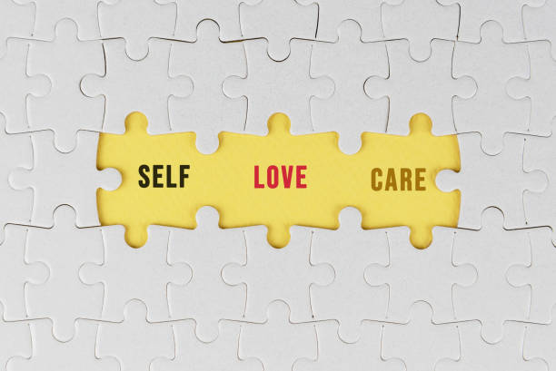 istock Self love and care. White jigsaw puzzle with text on three missing pieces on soft yellow. Love and take care of yourself concept. 1369624099