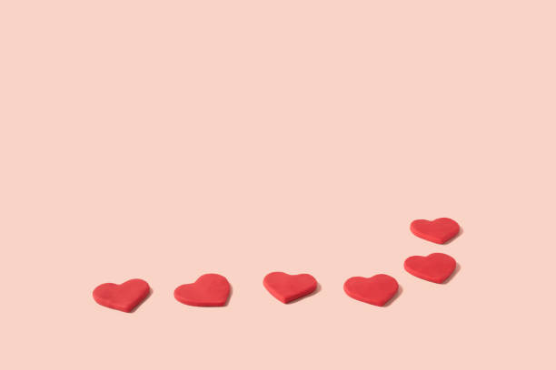 istock Pattern of red hearts made from modeling clay on a pastel pink background with copy space 1369624379