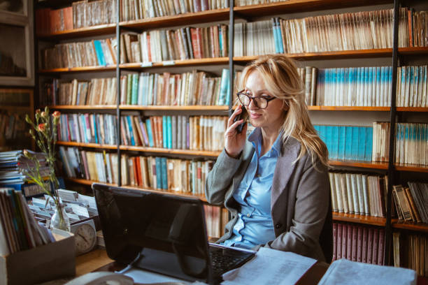 A middle-aged woman in a library A middle-aged woman works in a school library. Professor prepares classes at the department. librarian stock pictures, royalty-free photos & images